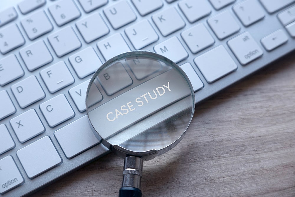 Magnifying glass over keyboard space bar labeled “Case Study” representing in-depth virtual training success stories.